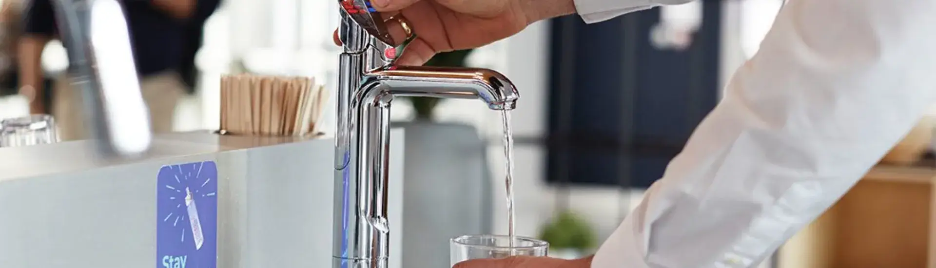 Man using zip HydroTap to fill glass with sparkling water